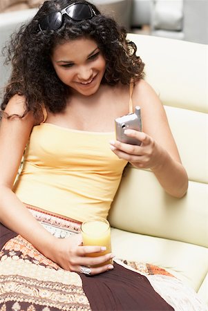 simsearch:625-01097695,k - Close-up of a young woman using a mobile phone and holding a glass of orange juice Foto de stock - Royalty Free Premium, Número: 625-01263611