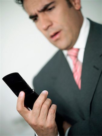 people shocked on phones - Close-up of a businessman looking at a mobile phone Stock Photo - Premium Royalty-Free, Code: 625-01263714