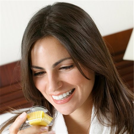 Close-up of a young woman holding a cupcake and smiling Stock Photo - Premium Royalty-Free, Code: 625-01263732