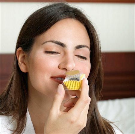 Close-up of a young woman smelling a cupcake Stock Photo - Premium Royalty-Free, Code: 625-01263854