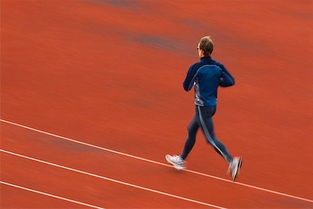 Rear view of a mid adult man running on a running track Stock Photo - Premium Royalty-Free, Code: 625-01744766