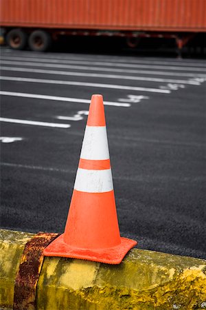 Close-up of a traffic cone with a cargo container in the background Stock Photo - Premium Royalty-Free, Code: 625-01746153