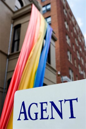 simsearch:625-01746293,k - Signboard in front of a rainbow flag hanging from a building Foto de stock - Royalty Free Premium, Número: 625-01746310