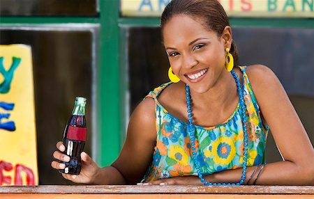 Portrait of a young woman leaning on a railing and holding a cola bottle Stock Photo - Premium Royalty-Free, Code: 625-01746413