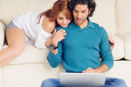 Young man using a laptop with a young woman leaning over him Stock Photo - Premium Royalty-Free, Code: 625-01746667
