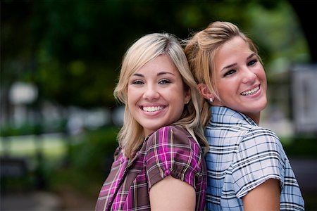 Portrait of two young women back to back and smiling Stock Photo - Premium Royalty-Free, Code: 625-01746668
