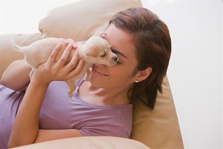 High angle view of a young woman playing with her puppy and lying on a couch Foto de stock - Sin royalties Premium, Código: 625-01746842