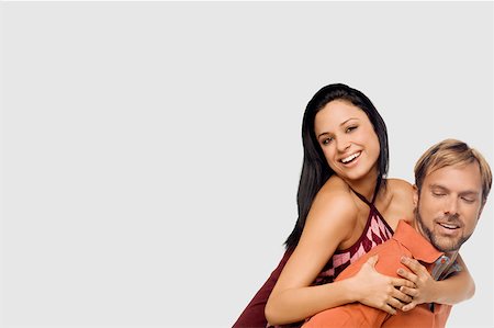 simsearch:625-01746515,k - Portrait of a young woman riding piggyback on a mid adult man Fotografie stock - Premium Royalty-Free, Codice: 625-01746914