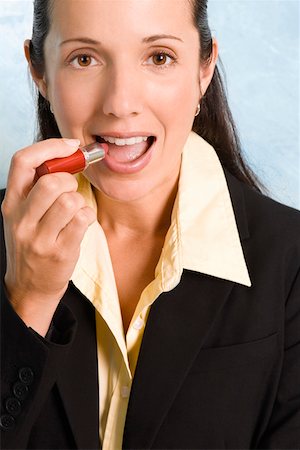 simsearch:625-02932995,k - Portrait of a businesswoman applying lipstick on her lips Stock Photo - Premium Royalty-Free, Code: 625-01747038