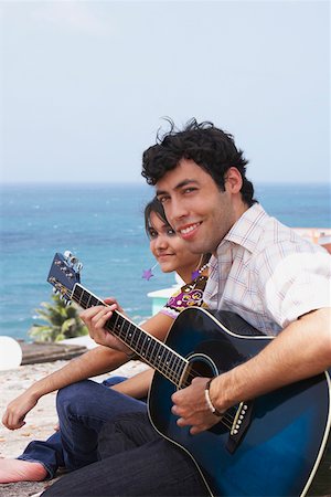 simsearch:625-01746515,k - Portrait of a young man sitting with a young woman and playing a guitar Fotografie stock - Premium Royalty-Free, Codice: 625-01747079