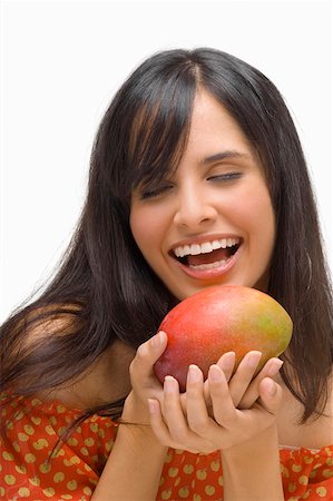 Close-up of a young woman holding a mango and laughing Stock Photo - Premium Royalty-Free, Code: 625-01747154