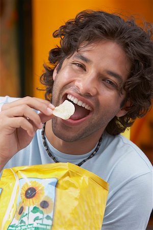 Portrait d'un jeune homme manger des pommes de terre frites Photographie de stock - Premium Libres de Droits, Code: 625-01747190