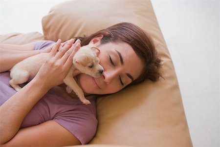 High angle view of a young woman lying on a couch and hugging a puppy Foto de stock - Sin royalties Premium, Código: 625-01747285