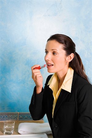 simsearch:6115-06778724,k - Side profile of a businesswoman applying lipstick on her lips Foto de stock - Sin royalties Premium, Código: 625-01747385