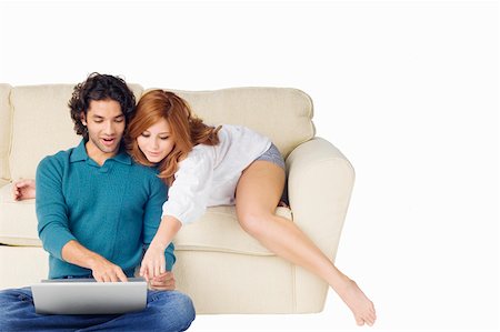 Young man using a laptop with a young woman leaning over him Stock Photo - Premium Royalty-Free, Code: 625-01747455