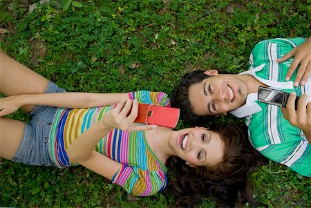 simsearch:625-01746733,k - Vue grand angle sur un jeune couple se trouvant dans un parc et en maintenant les téléphones mobiles Photographie de stock - Premium Libres de Droits, Code: 625-01747744