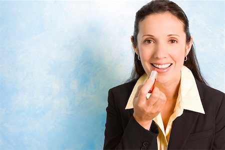 simsearch:625-00850993,k - Portrait of a businesswoman applying lipstick on her lips Stock Photo - Premium Royalty-Free, Code: 625-01747832
