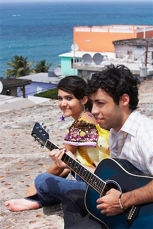 Young man sitting with a young woman and playing a guitar Stock Photo - Premium Royalty-Free, Code: 625-01747866