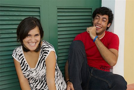 simsearch:625-01747054,k - Portrait of a young woman smiling with a young man sitting beside her and coughing Foto de stock - Sin royalties Premium, Código: 625-01747863