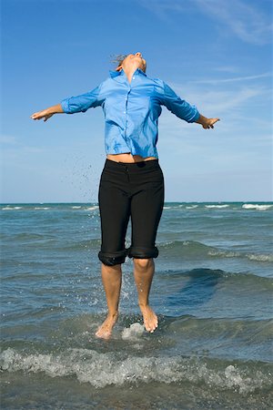 Mid adult woman jumping on the beach with her arms outstretched Stock Photo - Premium Royalty-Free, Code: 625-01748004