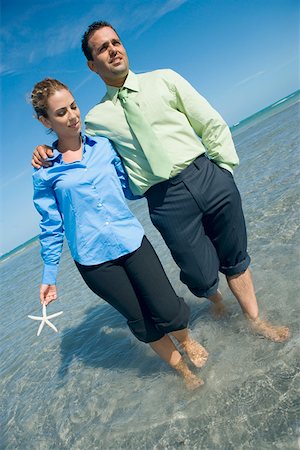 european woman holding fish - Mid adult couple wading on the beach with their arms around each other Stock Photo - Premium Royalty-Free, Code: 625-01748062