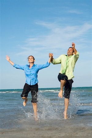 Mid adult couple jumping with holding each other hands on the beach Stock Photo - Premium Royalty-Free, Code: 625-01748070