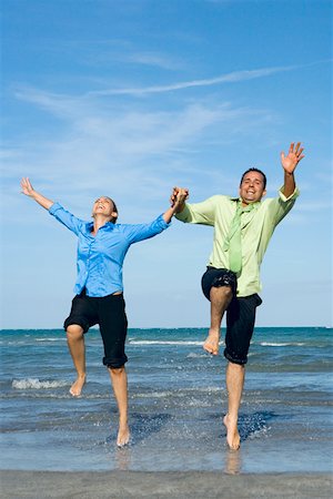 Mid adult couple jumping with holding each other hands on the beach Stock Photo - Premium Royalty-Free, Code: 625-01748073