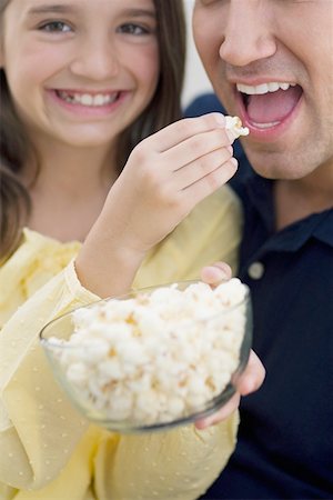 Portrait of a girl feeding popcorn to her father Stock Photo - Premium Royalty-Free, Code: 625-01748161