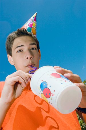 Low angle view of a boy drinking with a drinking straw Stock Photo - Premium Royalty-Free, Code: 625-01748272