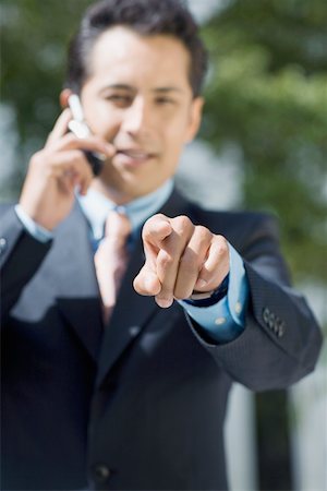 simsearch:625-02266709,k - Portrait of a businessman talking on a mobile phone and pointing forward Foto de stock - Sin royalties Premium, Código: 625-01748350