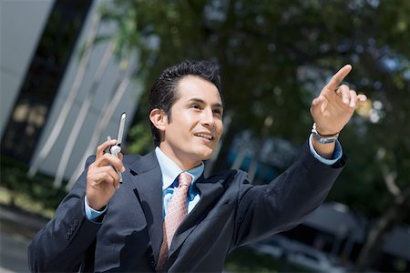 simsearch:625-01097695,k - Businessman holding a mobile phone and pointing upward Foto de stock - Royalty Free Premium, Número: 625-01748365