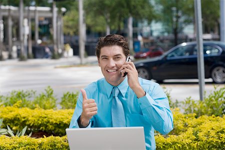 Portrait of a businessman talking on a mobile phone and showing a thumbs up sign Stock Photo - Premium Royalty-Free, Code: 625-01748377