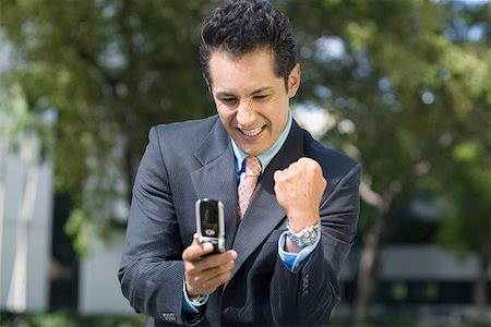 simsearch:625-02266709,k - Businessman looking at a mobile phone and making a fist Foto de stock - Sin royalties Premium, Código: 625-01748386