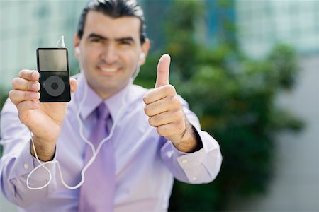 Portrait of a businessman showing an MP3 player and making a thumbs up sign Stock Photo - Premium Royalty-Free, Code: 625-01748382
