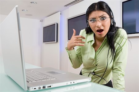 phone operator - Portrait of a young woman wearing a headset and standing in front of a laptop Foto de stock - Sin royalties Premium, Código: 625-01748419