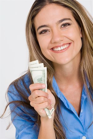 Portrait of a young woman holding American paper currency and smiling Stock Photo - Premium Royalty-Free, Code: 625-01748565