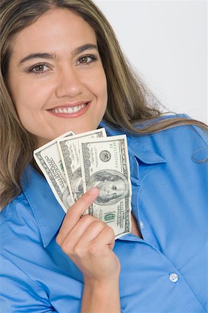 Portrait of a young woman holding American paper currency and smiling Stock Photo - Premium Royalty-Free, Code: 625-01748595