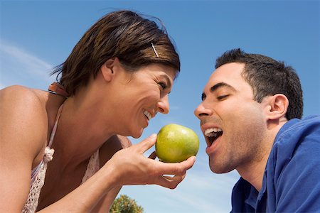 photo of a woman feeding her husband food - Mid adult woman feeding a green apple to a mid adult man Stock Photo - Premium Royalty-Free, Code: 625-01748665