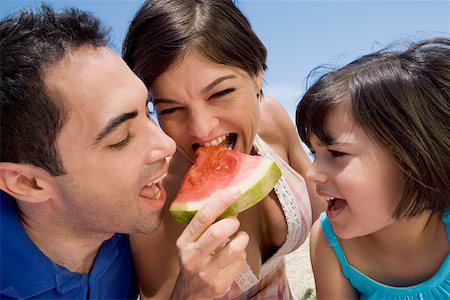 Mid adult couple eating a slice of watermelon with their daughter beside them Stock Photo - Premium Royalty-Free, Code: 625-01748709