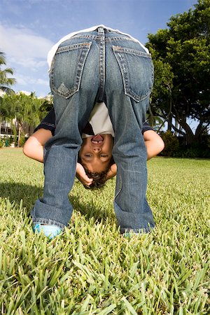 rear view of a boy bending over - Rear view of a boy looking through his legs Stock Photo - Premium Royalty-Free, Code: 625-01748717