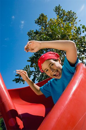 Boy sliding down playground slide stock photo