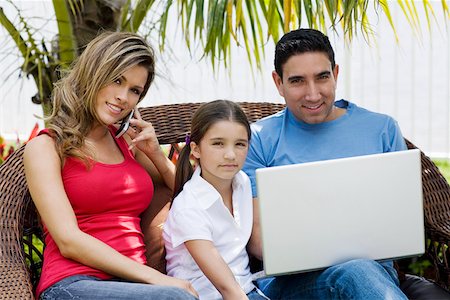 Portrait of a mid adult man using a laptop with a girl and a young woman sitting beside them Stock Photo - Premium Royalty-Free, Code: 625-01748796