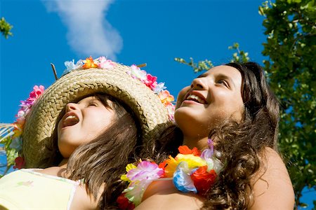Low angle view of two girls wearing flowers and smiling Stock Photo - Premium Royalty-Free, Code: 625-01748820