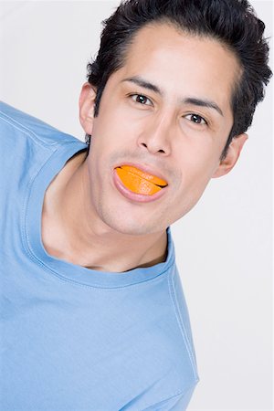 people with fruits cutout - Portrait of a young man holding a slice of an orange in his mouth Stock Photo - Premium Royalty-Free, Code: 625-01748835