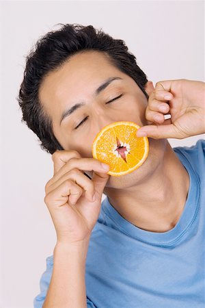 people with fruits cutout - Close-up of a young man smelling a slice of an orange Foto de stock - Sin royalties Premium, Código: 625-01748868