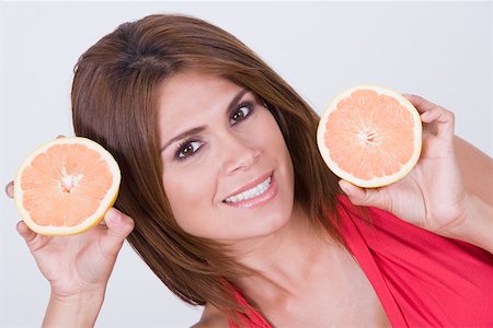 simsearch:625-01748850,k - Portrait of a young woman holding slices of oranges Foto de stock - Sin royalties Premium, Código: 625-01748860