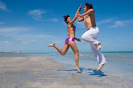 Side profile of a mid adult couple doing high-five on the beach Stock Photo - Premium Royalty-Free, Code: 625-01748883