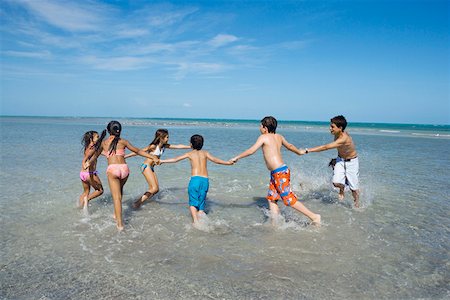 preteen girl swimsuit rear view - Children playing with holding each other hands on the beach Stock Photo - Premium Royalty-Free, Code: 625-01748907