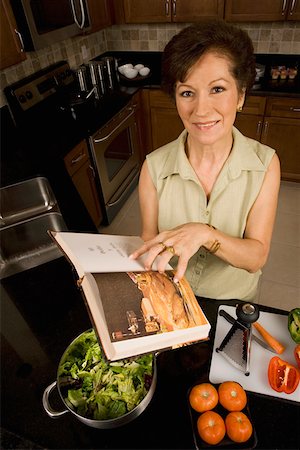Portrait of a senior woman holding a cookbook in the kitchen and smiling Foto de stock - Sin royalties Premium, Código: 625-01748975