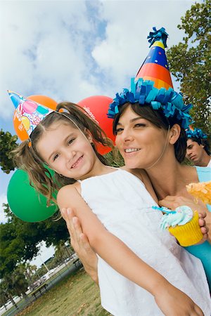 parents and children and cupcakes - Close-up of a girl standing with her mother and smiling Stock Photo - Premium Royalty-Free, Code: 625-01749023
